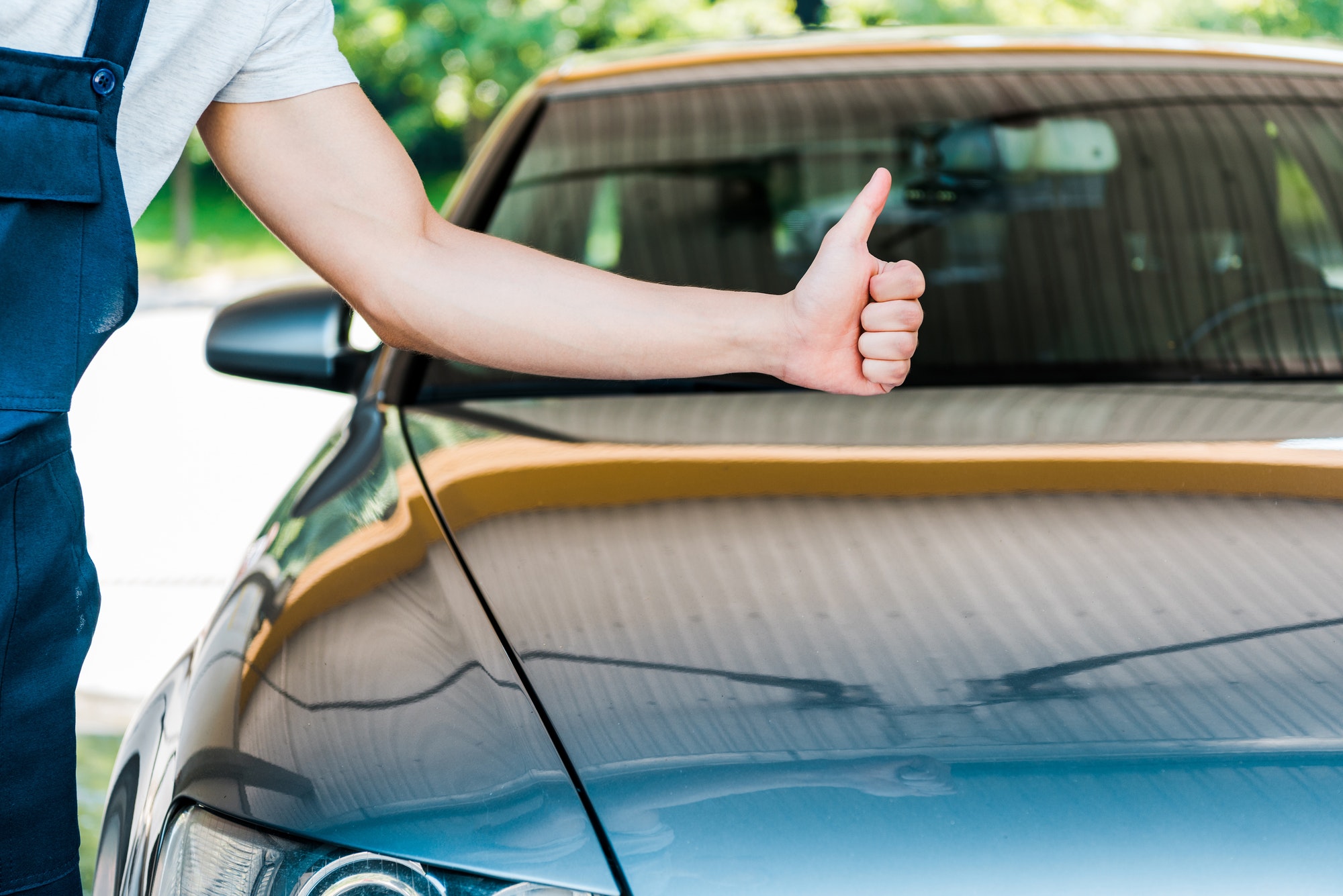 cropped view of car washer showing thumb up near grey car